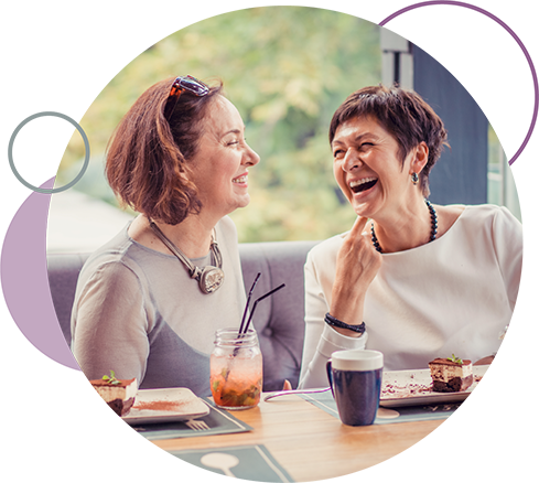 Two woman laughing over coffee after a credit card purchase.